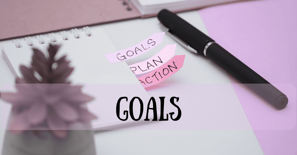 Goals planning workspace with pink sticky notes reading 'GOALS', 'PLAN', 'ACTION' on notebook with pen and succulent plant